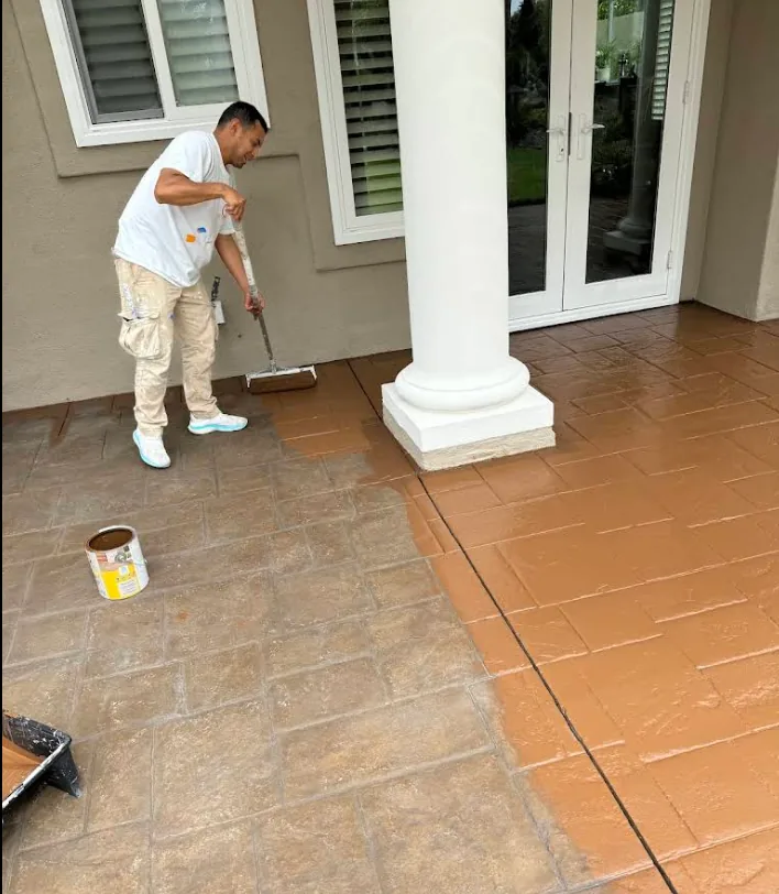 Applying a terracotta coating to a stamped concrete patio beside a white column