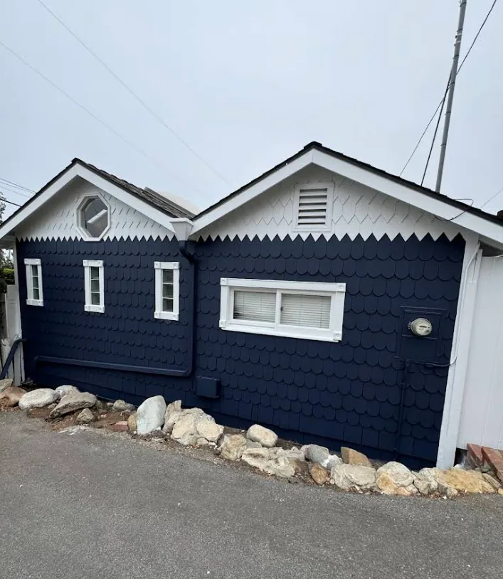 The same house from the front: navy shingle siding, white window trim and fascia
