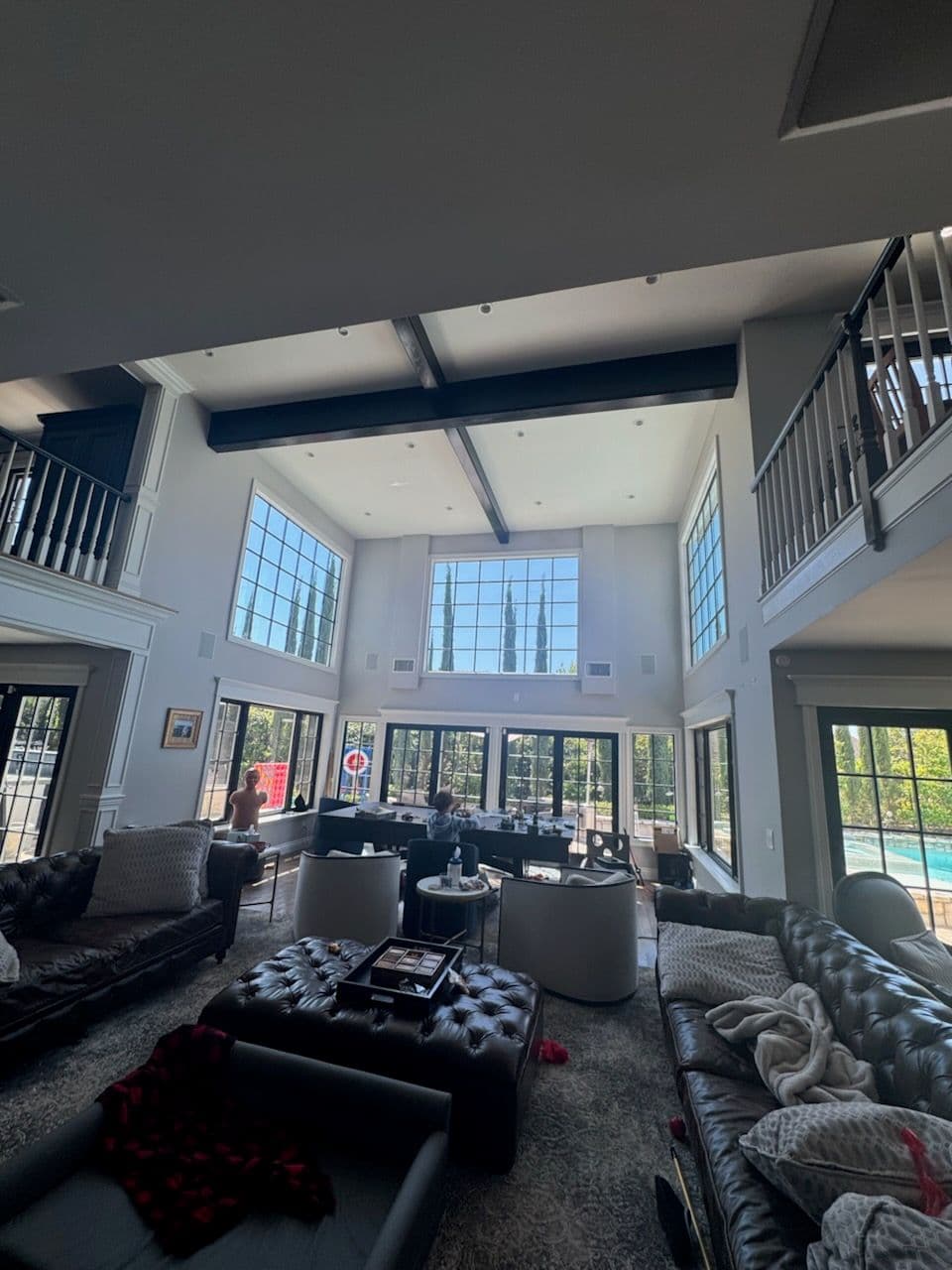 Spacious modern living room with large windows and elegant furnishings overlooking a pool.