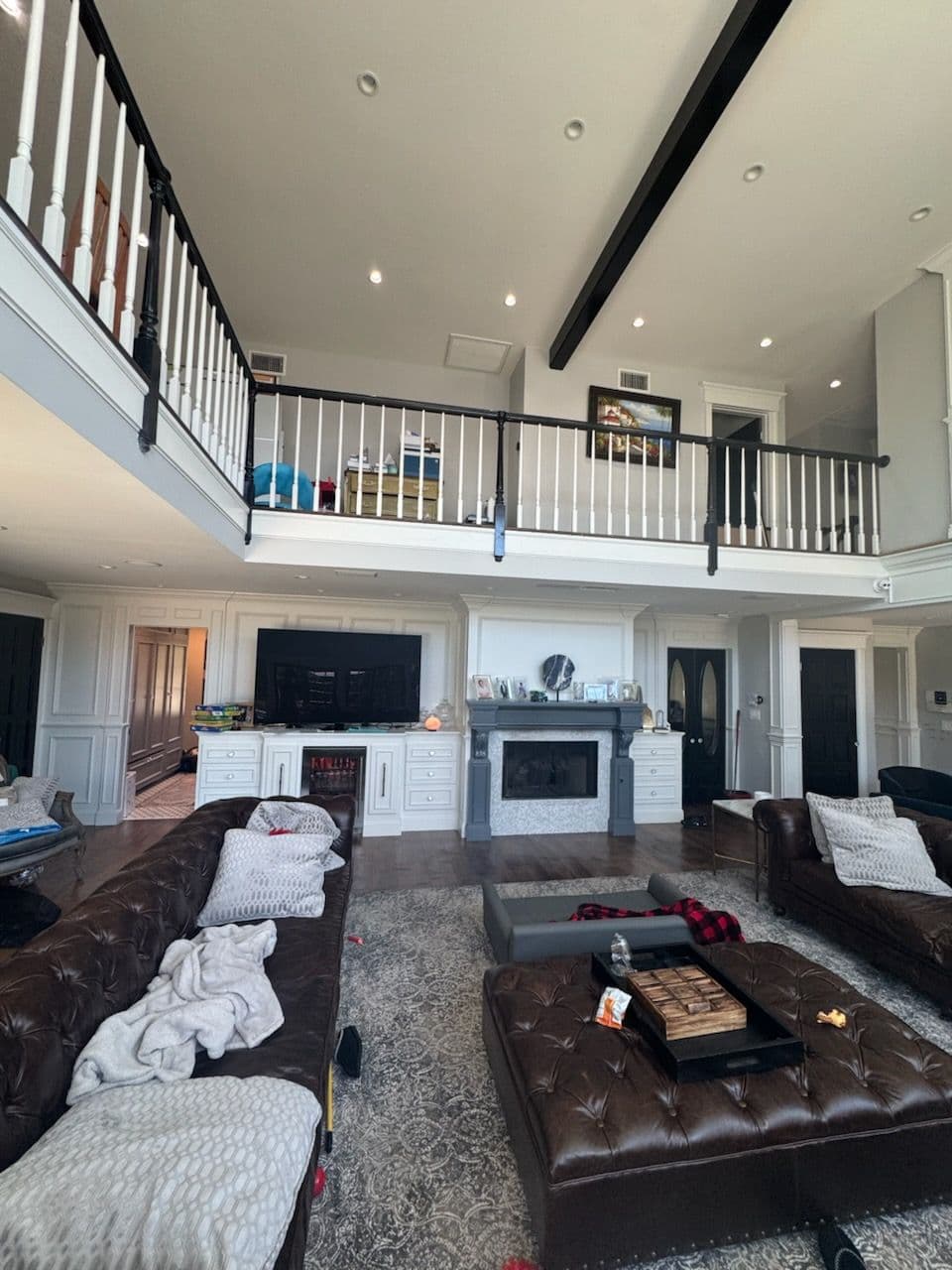 Spacious living room with two levels, brown leather sofas, and modern decor.