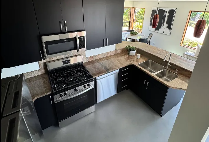 Granite countertop installed over dark cabinets with a gas range and stainless sink